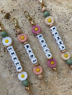 three key chains with flowers and letters on them