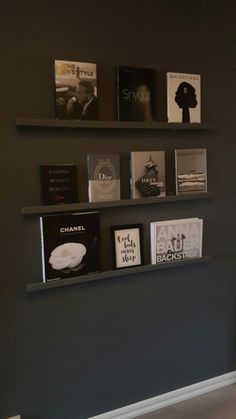 some books are sitting on the shelves in front of a wall that is painted dark gray