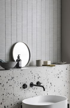 a white sink sitting under a bathroom mirror next to a wall mounted faucet