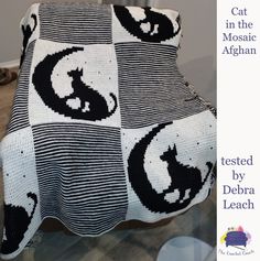 a black and white crocheted blanket with cats on it