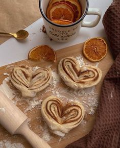 some oranges and cinnamon rolls are on a cutting board next to a cup of coffee