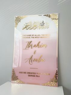 a pink and gold wedding card with the name of the bride in arabic on it