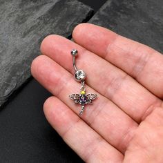 Product DetailsClear Yellow Purple Gem Dragonfly Dangle Belly Ring The delightful dragonfly on this 14 gauge navel ring is so lovely it is almost magical. It is made with a 3/8 inch 316L surgical grade stainless steel curved barbell with a 5mm top ball end. The bottom ball end is 8mm and set with a large clear gem. Dangling beneath it is a dragonfly charm, with openwork wings and cohesive detailing that will not overwhelm. It also features a purple gem body and yellow gem head for a striking tou Dragonfly Belly Button Piercing, Belly Piercing Jewelry, Button Piercing, Jewelry Promotion, Yellow Gems, Dangle Belly Rings, Purple Gems, Tongue Rings, Dragonfly Charm