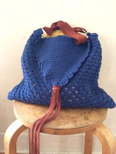 a blue crocheted bag sitting on top of a stool