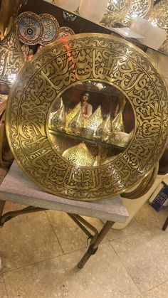 an ornate gold plate on top of a table next to other decorative plates and bowls