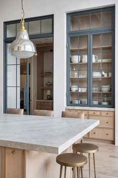 a kitchen island with two stools in front of it and an open pantry behind it