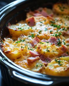 a casserole dish with ham, potatoes and cheese in a crock pot