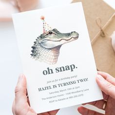 a person holding up a birthday card with an alligator on it