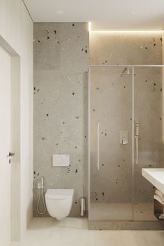 a bathroom with a toilet, sink and shower in it's center wall that is covered in black speckles