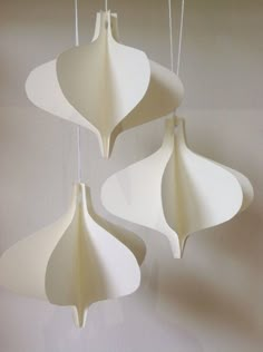 three white ornaments hanging from strings in the shape of flowers on a wall or ceiling