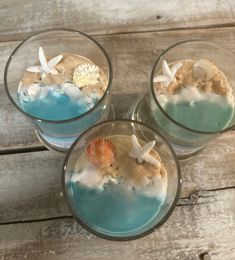 three glasses filled with sand and sea shells