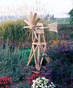 a wooden windmill sitting in the middle of a garden