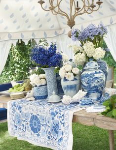 a table with blue and white vases sitting on it's side under a tent