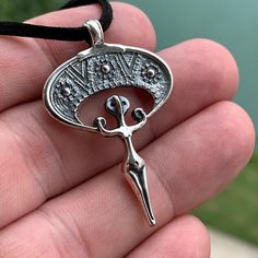 a hand holding a silver pendant with scissors on it