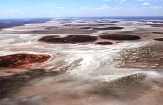 an aerial view of the desert with many patches of dirt and water on it's surface