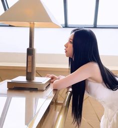 a woman sitting at a table with a remote control in her hand and looking out the window