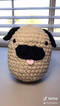 a crocheted stuffed animal with a black nose and brown body sitting on top of a table