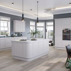 a large kitchen with white cabinets and an island in the middle is lit by pendant lights