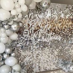 white and silver balloons are hanging on the wall in front of a mirror mosaic backdrop