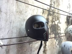 a helmet hanging on the side of a wall next to some balls and wires in front of it