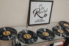 some black and gold records sitting on top of a glass table next to a framed poster