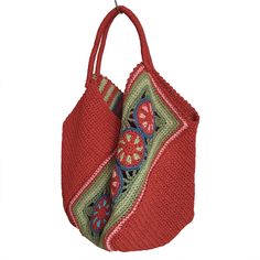 a red handbag hanging from a hook on a white wall with an embroidered design