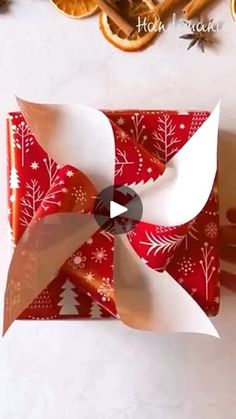 an origami box is decorated with red and white paper, surrounded by orange slices