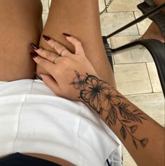 a woman's leg with flowers on it and her hand resting on the thigh