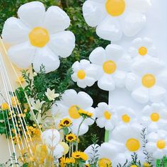 white and yellow flowers are on display in front of a large balloon sculpture that looks like it's floating