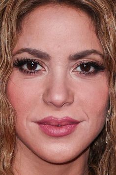 a close up photo of a woman with long hair and brown eyes, wearing black eyeliners