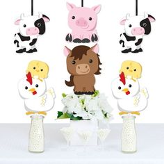 a table topped with vases filled with white flowers and farm animals hanging from the ceiling