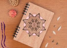 a wooden notebook with an intricate design on the cover and some flowers next to it