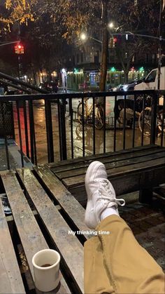 a person's feet resting on a bench with their coffee cup in front of them