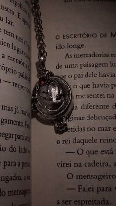 an open book with a chain attached to it and a heart shaped locke hanging from the front