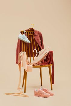 a wooden chair with clothes on it and a pair of pink shoes next to it