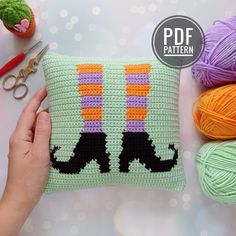 a crocheted pillow with two cats on it and some yarn next to it