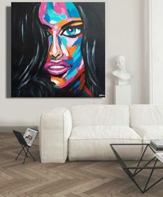 a living room with a white couch and large painting on the wall above it's coffee table