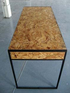 a coffee table made out of plywood and black metal frame on concrete flooring