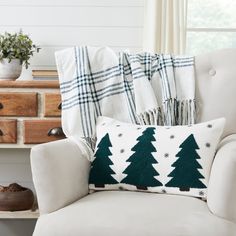 a christmas tree pillow sitting on top of a white chair next to a wooden dresser