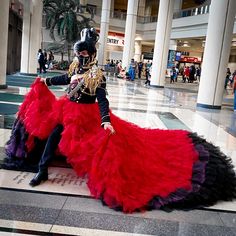 a woman in a red and black dress sitting on the ground