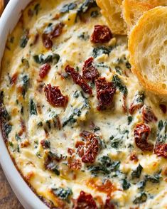 spinach and cheese dip in a white bowl with slices of bread on the side