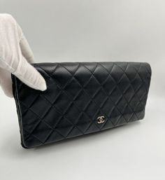 Introducing the Chanel Matelasse Lambskin Leather CC Clutch bag in Black, an exquisite accessory that is sure to make a statement. This clutch is made from black lambskin leather that has been quilted with the signature Chanel pattern and finished with antique silver hardware. The interior is lined with a playful quilted maroon nylon and features a main zippered compartment as well as a zippered pocket for your valuables. This bag is in immaculate pre-owned condition and has barely been used. It