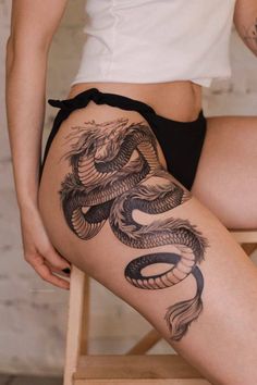 a woman's thigh with a tattoo on it and a dragon design on the side