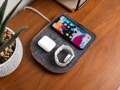 an apple watch and ear buds are sitting on a wooden table next to a plant