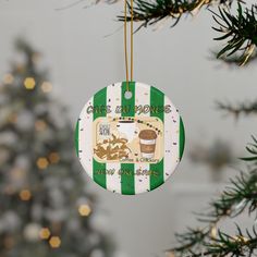 a green and white ornament hanging from a christmas tree with a cup of coffee on it