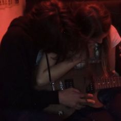 two people sitting next to each other playing guitar