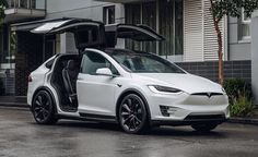 a white tesla electric car parked in front of a building with its doors open and it's door opened