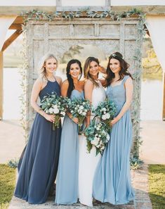 the bridesmaids are posing in front of an arch with greenery and flowers