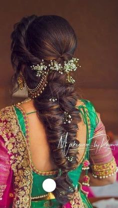 a woman with long hair in a green and pink sari, braided into a half - up hairstyle