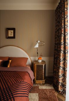 a bed sitting next to a window in a room with striped wall paper on the walls